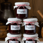 Confiture de prunes maison en pots de verre avec prunes fraîches sur table rustique