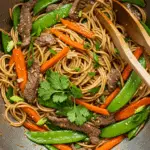 Wok de légumes au bœuf avec nouilles chinoises dans un wok traditionnel noir
