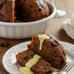 Christmas pudding traditionnel flambé au cognac sur assiette blanche avec sucre glace