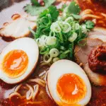 Ramen bouillon épicé œufs marinés jaunes coulants fumant bol japonais